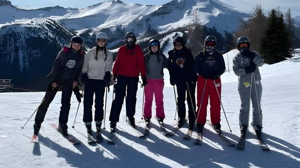Un grupo de estudiantes de la Bawlf School está en invierno en una ladera cubierta de nieve con montañas al fondo.