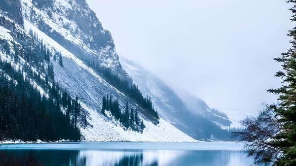 Un lago tranquilo con agua turquesa y montañas cubiertas de nieve al fondo en la Bawlf School.