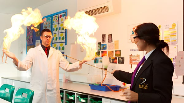 Dos personas realizan un experimento en el laboratorio del Baxter College con humo visible ascendiendo.