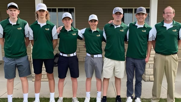 Un grupo de estudiantes de la Beckman Catholic School está de pie en uniforme verde y blanco frente a un edificio de ladrillo.
