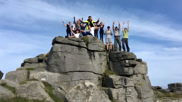 Un grupo de estudiantes de la Bedales School está en un saliente rocoso bajo un cielo azul.