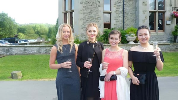 Cuatro estudiantes de la Bedstone School están juntas frente a un edificio de piedra con mucho verde.