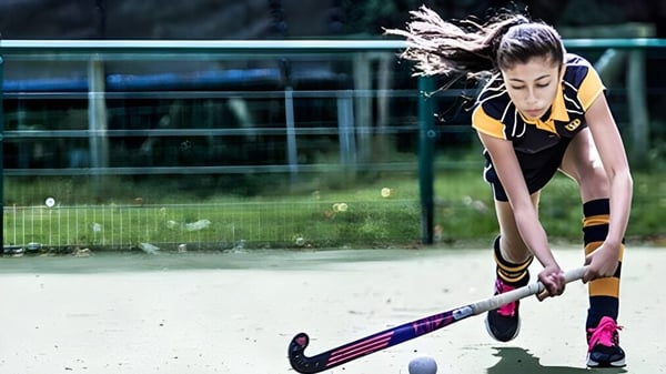 Una joven deportista de la Bedstone School se concentra en la pelota de hockey en el campo deportivo.