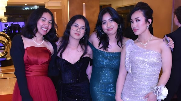 Cuatro alumnas del Belmont City College posan juntas en una sala de eventos.