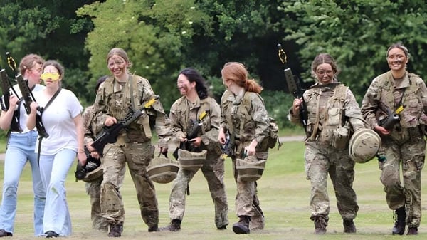 Personal militar en uniformes de camuflaje camina junto por un campo en el terreno de la Benenden School.