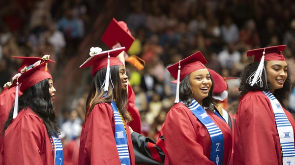 Un grupo de graduados en togas rojas celebra su graduación en la Benowa State High School.