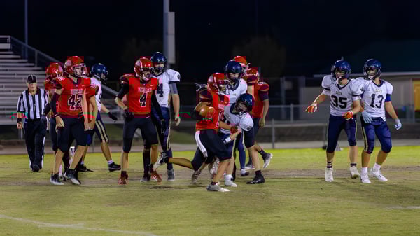 Jugadores de la Berean Baptist Academy luchan durante un partido de fútbol en el campo bajo las luces.