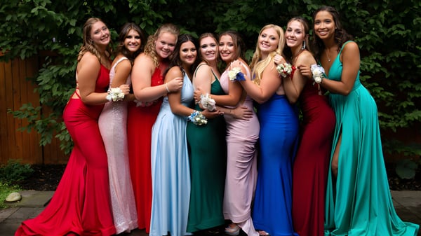 Estudiantes de la Berkhamsted School posan juntas en coloridos vestidos en el área exterior verde.