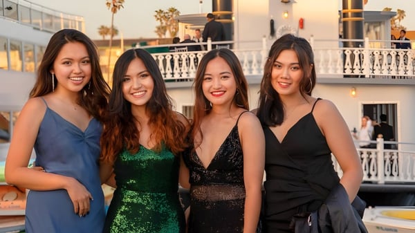 Cuatro estudiantes de la Besant Hill School posan juntas frente a un edificio con balcón y palmeras en un evento al aire libre.