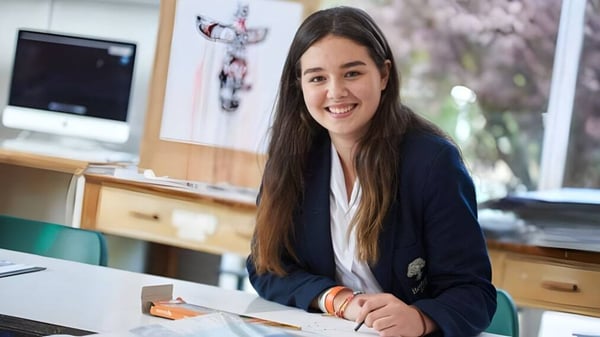 Una estudiante sonríe sentada en su escritorio en el aula de la Bethany School.