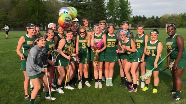 Un grupo de jóvenes estudiantes de la Bishop Brady High School está de pie en un campo de hierba sosteniendo un globo colorido.
