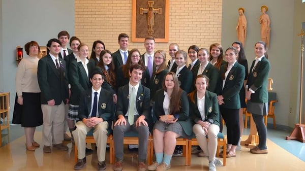 Un grupo de estudiantes se reúne en una sala con imágenes religiosas en el campus de la Bishop Brady High School.