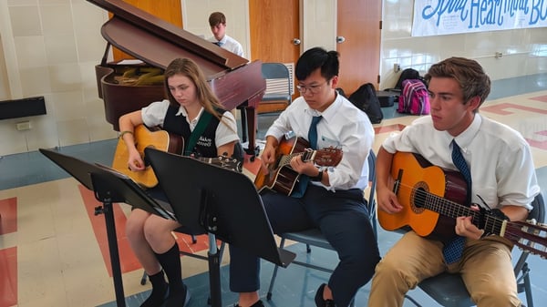 Un grupo de estudiantes toca guitarras y actúa con otros instrumentos en el campus de la Bishop Carroll High School.