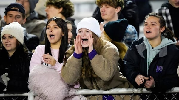 Un grupo de estudiantes en el campus de la Bishop Guilfoyle Catholic High School celebra juntos al aire libre con ropa de invierno.