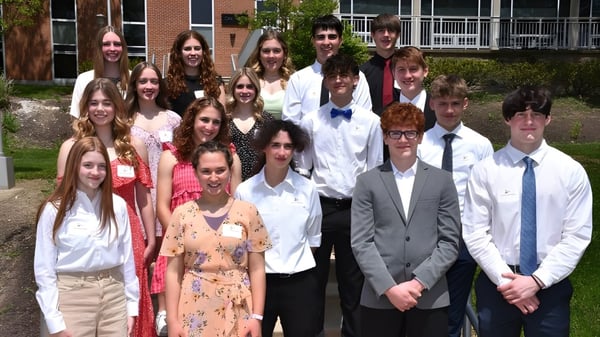Un grupo de estudiantes está en el área exterior frente a un edificio de ladrillo en el campus de la Bishop Guilfoyle Catholic High School.