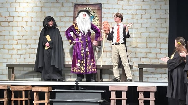 Estudiantes de la Bishop Heelan Catholic High School realizan una obra de teatro con elaborados disfraces en el escenario.