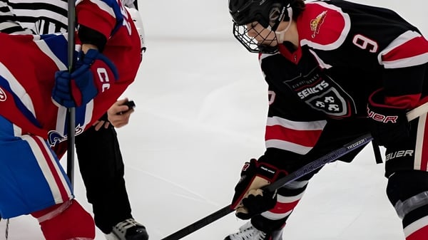 Dos jugadores de hockey de la Bishop Kearney High School se enfrentan en el hielo y cruzan sus palos.