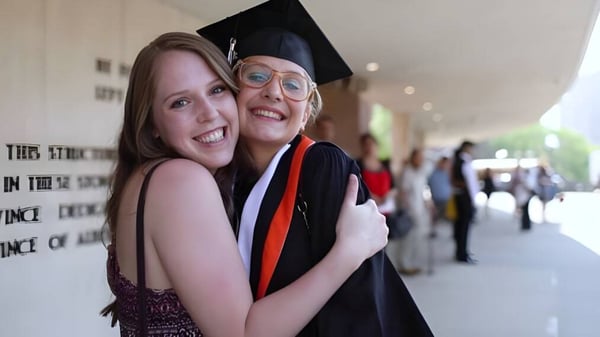 Dos estudiantes de la Bishop McNally High School se abrazan durante la fiesta de graduación frente al edificio universitario.
