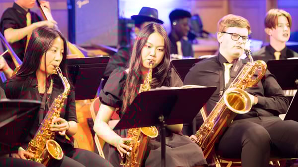 Un grupo de músicos, incluidos saxofonistas, se presenta en el escenario del Bishop’s Stortford College.