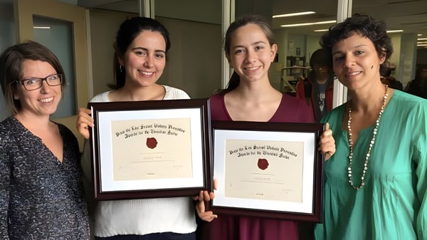 Cuatro mujeres del Bloor Collegiate Institute sostienen juntas certificados enmarcados en un interior.