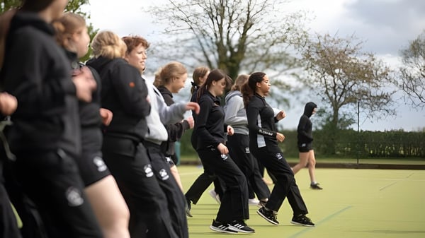 Un grupo de estudiantes de la Bloxham School está en un campo de hierba frente a árboles.