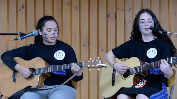 Dos estudiantes tocan guitarras acústicas y cantan en una sala revestida de madera en Blue Mountain College.