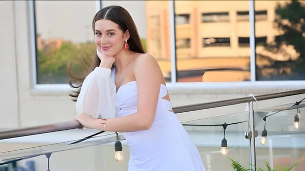 Una joven mujer en un vestido blanco está en un balcón con vista a la ciudad en el Blue Valley School District.