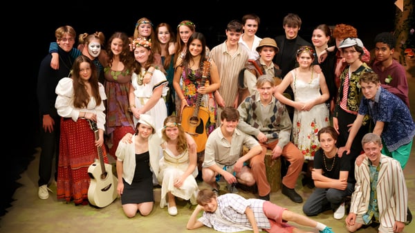 Un grupo de estudiantes de la Blundells School se reúne en un escenario y algunos están en el suelo.