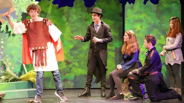 Estudiantes de Bodmin College están en trajes coloridos en un entorno de bosque verde.