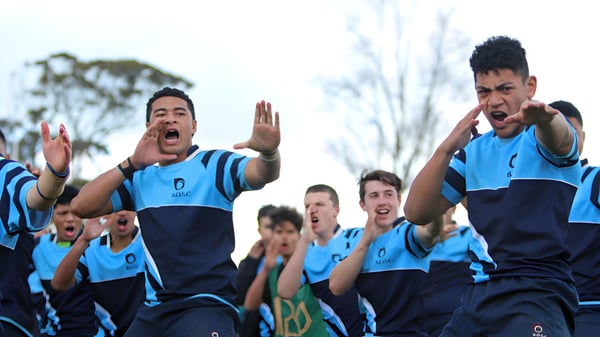 Un grupo de estudiantes de Botany Downs Secondary College celebra en el campo deportivo con sus uniformes deportivos azules.