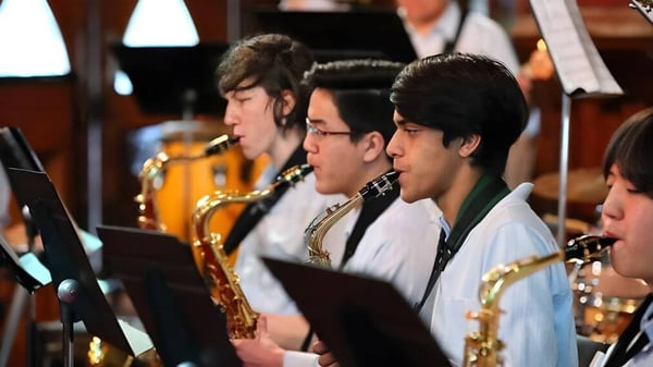 Un grupo de estudiantes de Botany Downs Secondary College toca varios instrumentos de viento en un escenario.