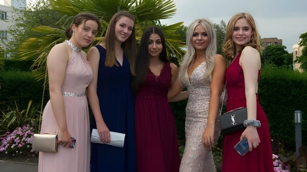 Un grupo de cinco estudiantes de Bournemouth Collegiate School posan en el área exterior tropical con palmeras de fondo.