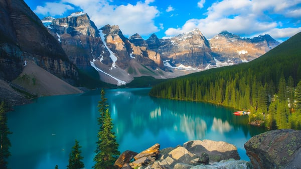 Un tranquilo lago turquesa frente a montañas nevadas y un bosque perenne en la naturaleza cerca de la Bowness High School.