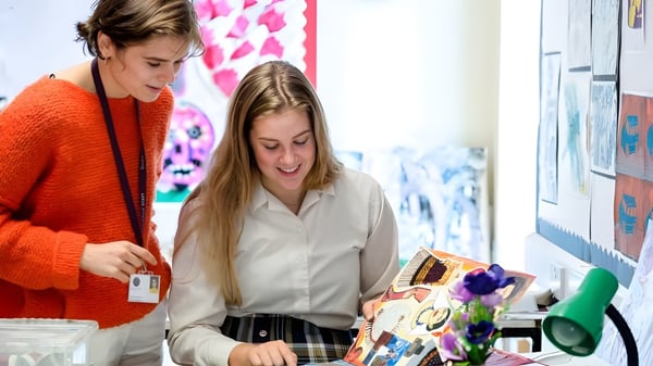 Dos estudiantes de la Bredon School están en una sala con arte colorido en las paredes.