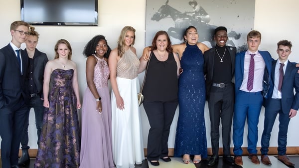Un grupo de personas en ropa formal está frente a una pared con obras de arte en el campus de la Bredon School.