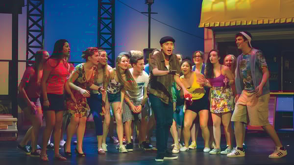 Un grupo de estudiantes en el escenario de la Brentwood College School frente a luces y equipo de escenario.