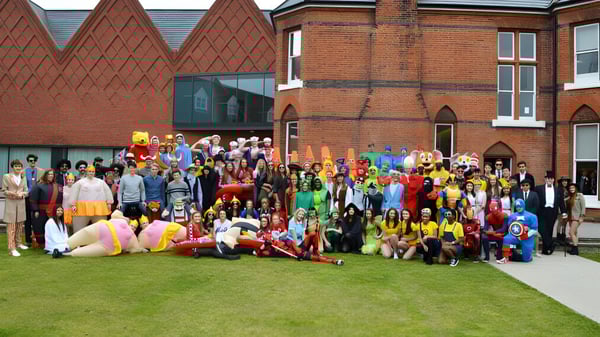 Un grupo de estudiantes disfrazados se reúne frente al histórico edificio de ladrillo de la Brentwood School.