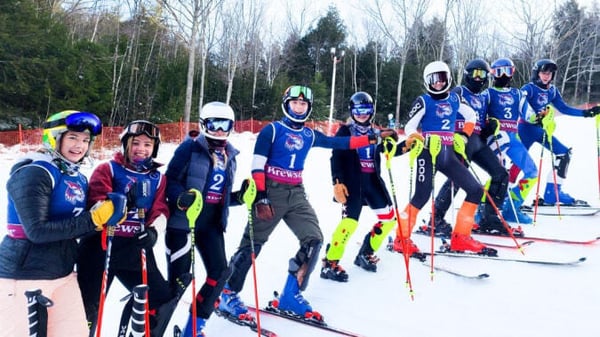 Un grupo de esquiadores con uniformes coloridos está de pie en una pendiente cubierta de nieve en el terreno de la Brewster Academy.
