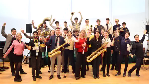 Un grupo de estudiantes del Brighton College con instrumentos musicales se reúne en una sala de ensayo.