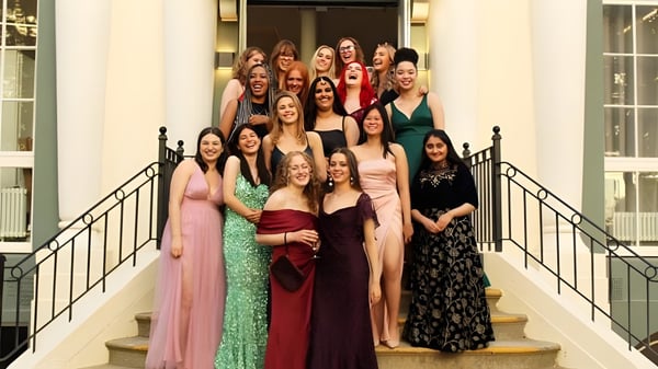 Alumnas de Brighton Girls posan juntas en una escalera con ropa festiva frente a un fondo decorativo.