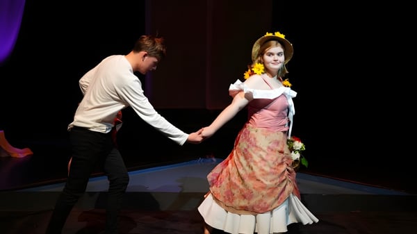 Un hombre y una mujer en ropa formal bailan en una actuación en el escenario de la Brighton Secondary School.