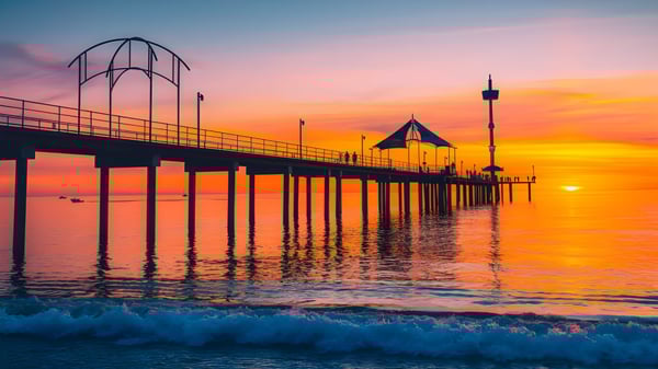 Un muelle se extiende sobre aguas tranquilas frente a la colorida puesta de sol en el campus de la Brighton Secondary School.