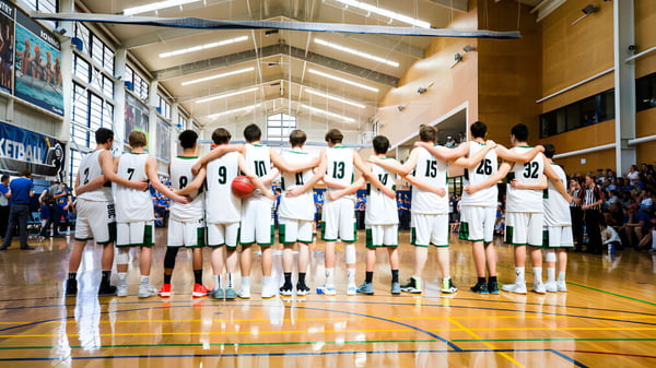 Un grupo de jugadores de baloncesto está reunido en la cancha de baloncesto del Brisbane Boys' College.