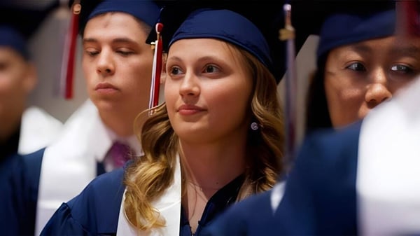 Un grupo de graduadas y graduados en togas azules durante la ceremonia de graduación de la British International School Houston.