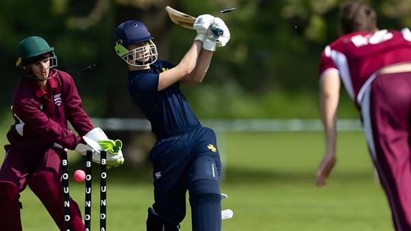 Un jugador de cricket de la Bromsgrove School golpea la pelota en un campo verde frente a dos jugadores más.