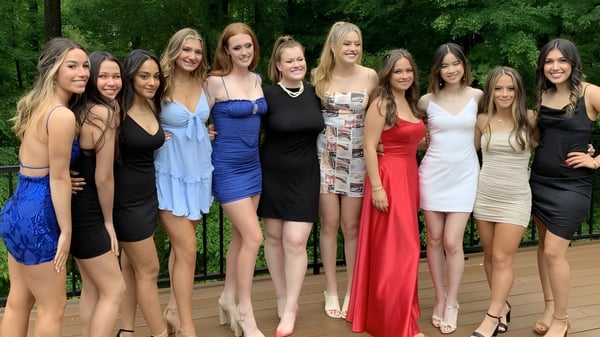 Un grupo de jóvenes mujeres en vestidos coloridos posan juntas en el verde en el terreno del Brooke House College.