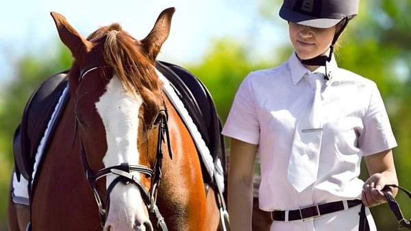 Una persona junto a un caballo marrón y blanco en un prado en el terreno de la Brookswood Secondary School.