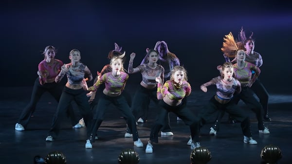 Un grupo de bailarinas y bailarines presenta una colorida pieza de danza en el escenario de la Bryanston School.