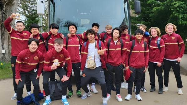 Un grupo de estudiantes de la Buckswood School lleva uniformes deportivos rojos y posan juntos al aire libre.
