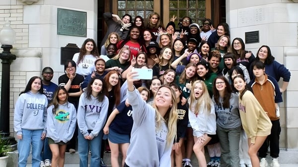 Un grupo de estudiantes posa para una foto grupal frente a un edificio de ladrillo en el campus de Buffalo Seminary.
